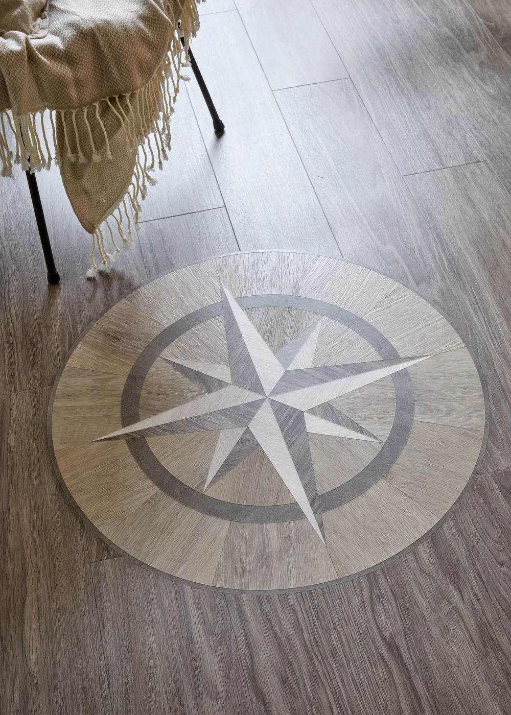 Détail d’une rose des vents Amtico incrustée dans un sol Wharf Oak