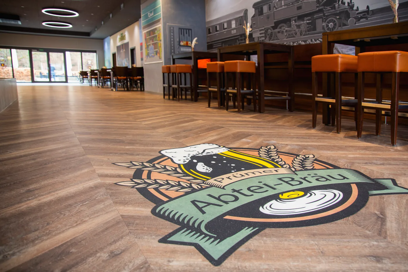 Brasserie au sol Amtico Reclaimed Oak en chevron, avec logo sur mesure incrusté dans le sol