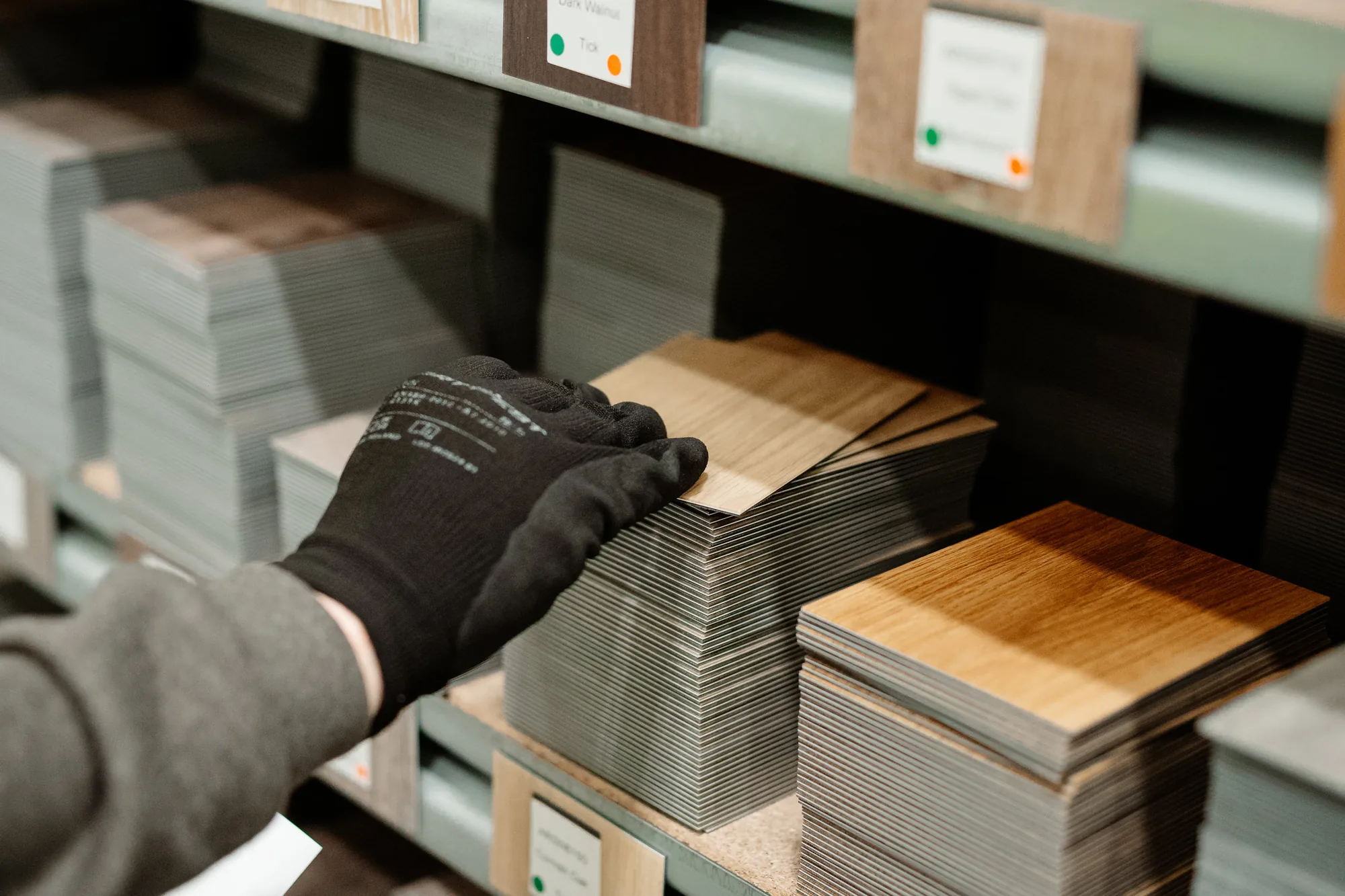 Main gantée feuilletant des échantillons Amtico rangés dans une échantillothèque