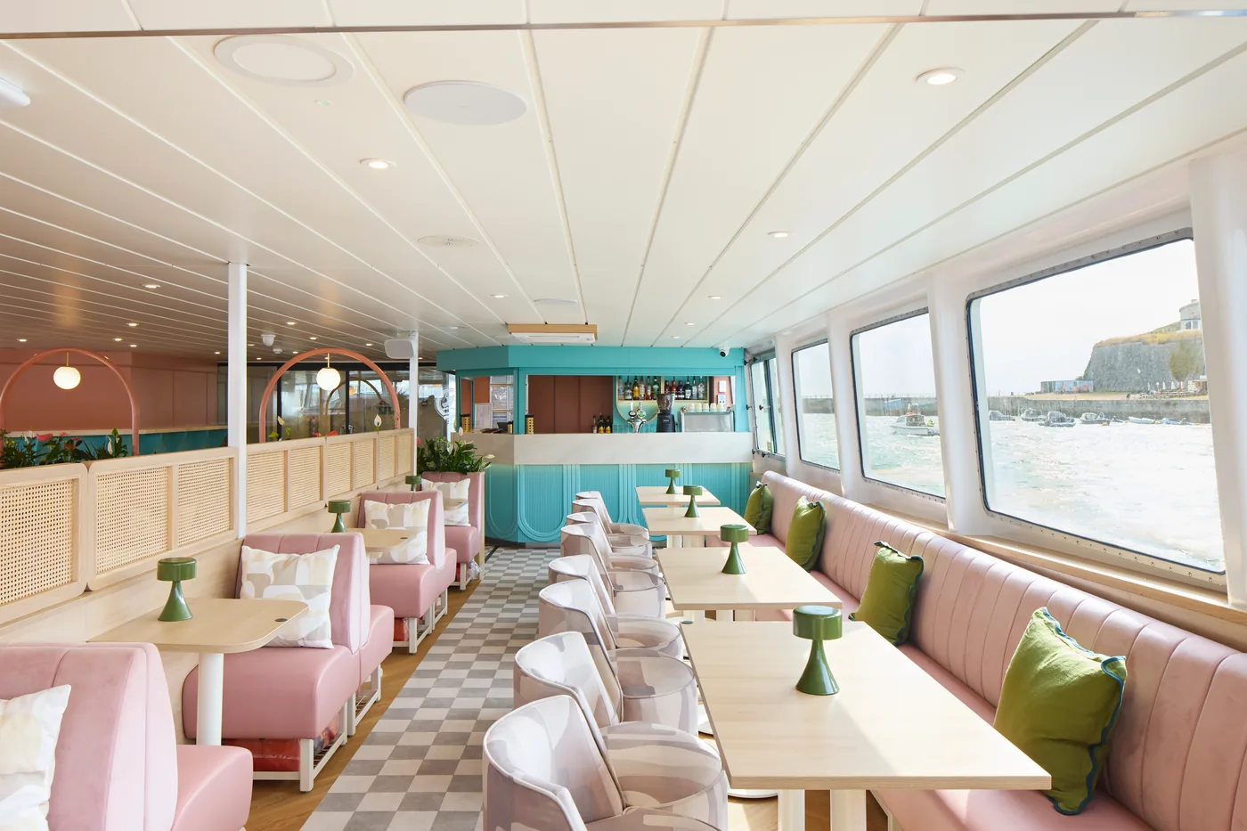 Salle de restauration panoramique à bord d’un bateau, avec un sol aspect bois.