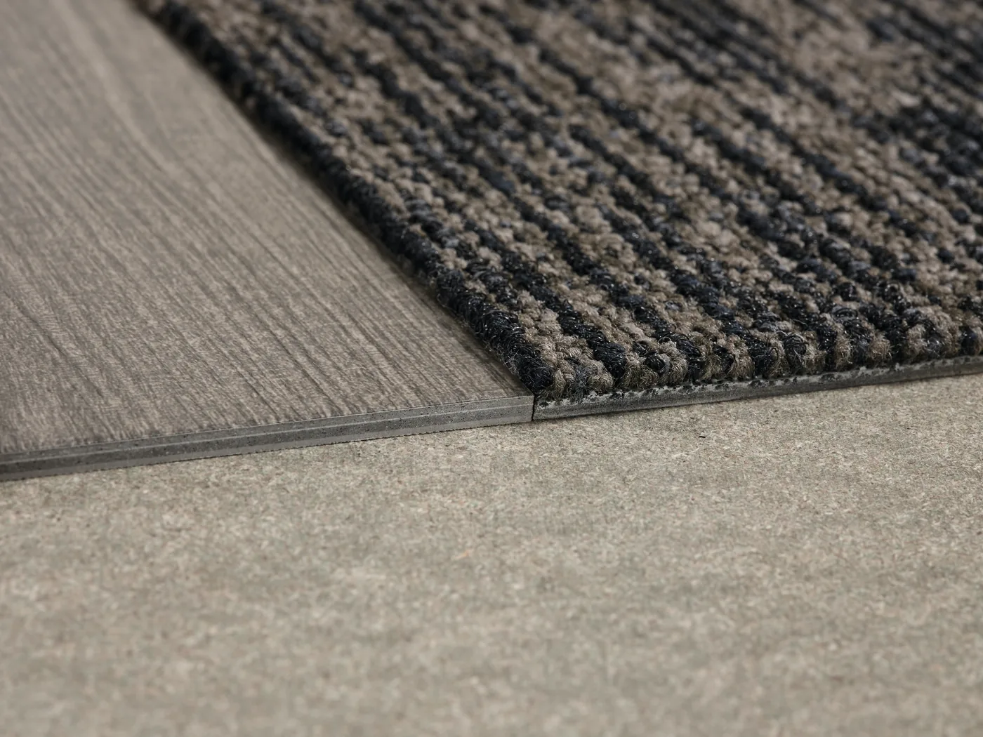 Gros plan sur la texture striée d’un tapis d’entrée et sa jonction avec le sol.